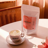 Café with a cup of coffee and a package of GROWND coffee on a table.